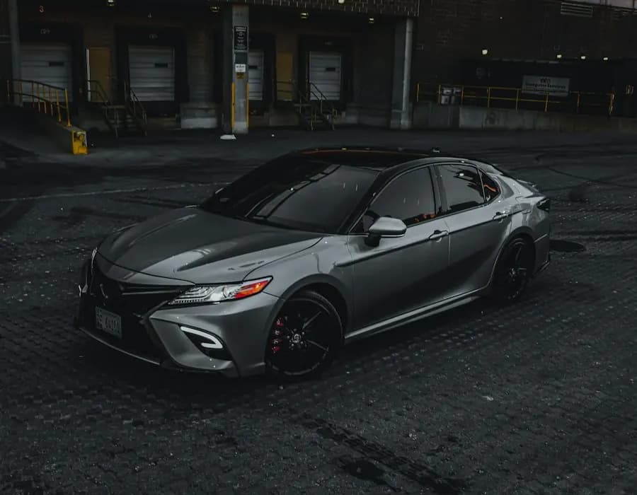 A gray sedan parked in a dark garage