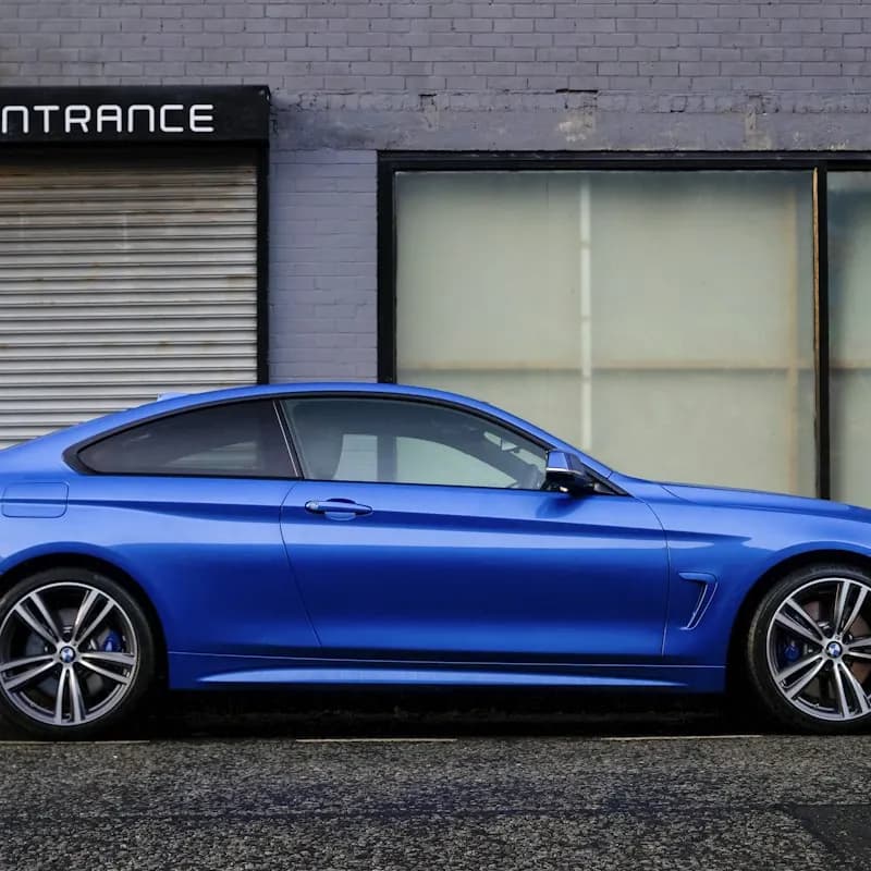A blue coupe in front of a building