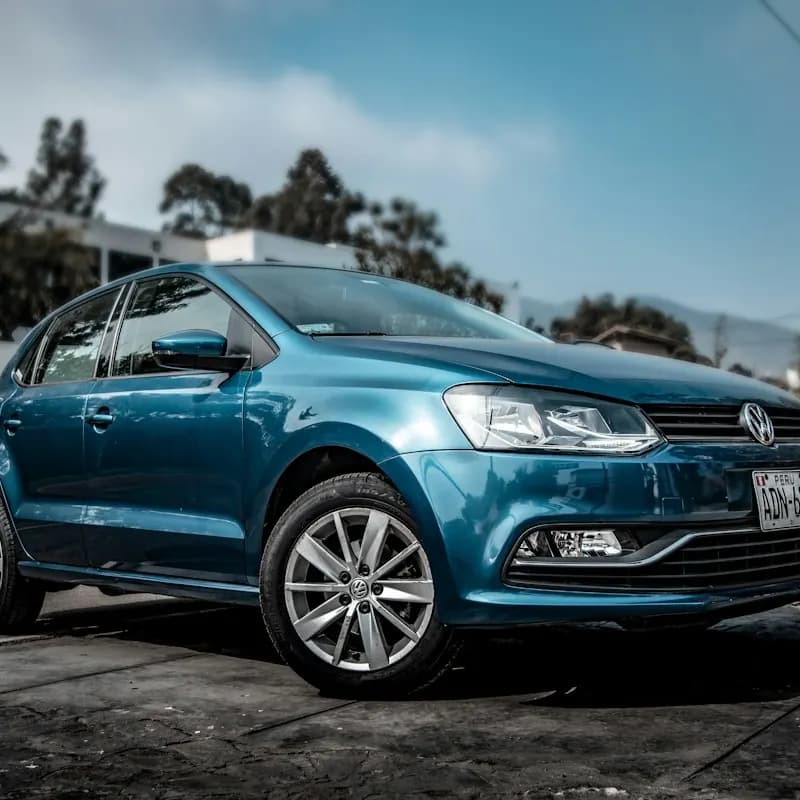 A blue hatchback parked on gravel