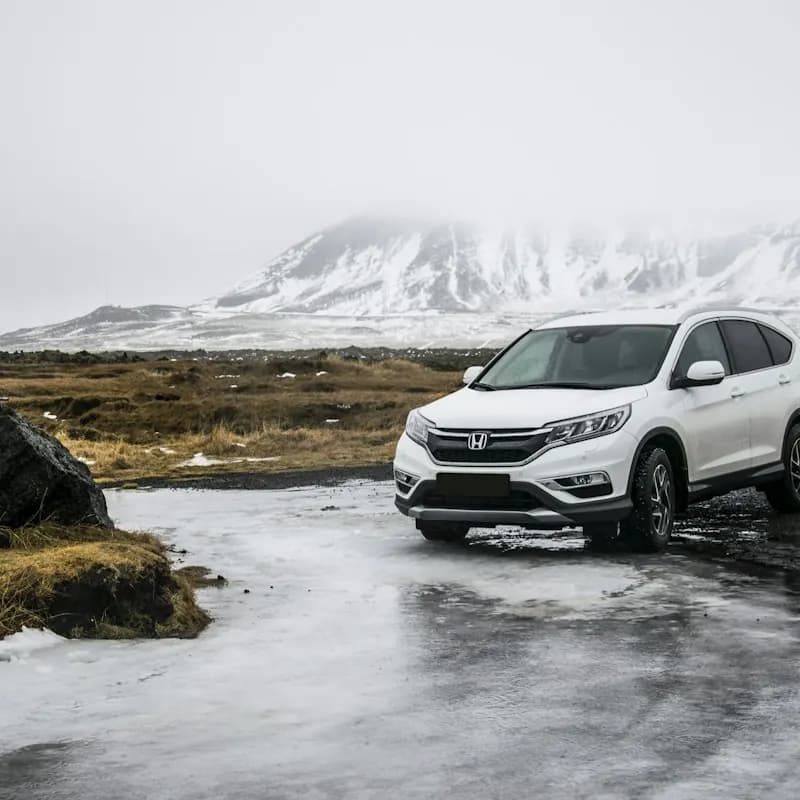 A white compact SUV on a rocky shore